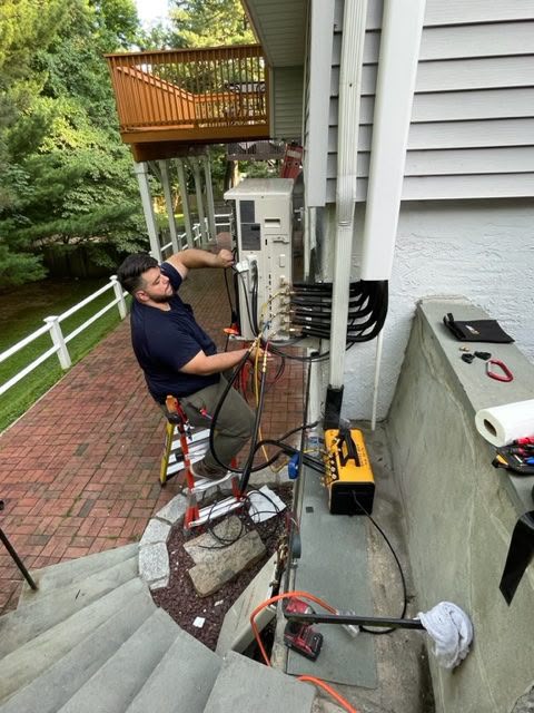 AD Air Technical technician servicing an outdoor HVAC condenser at a New York home